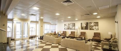 A lobby with checkered flooring, multiple seating areas, and wall-mounted artwork.
