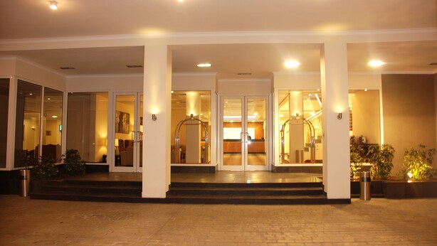 Entrada de hotel con suelo adoquinado de ladrillo, puertas de vidrio y una escalera que conduce a la entrada.