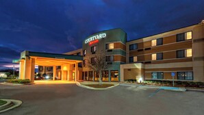 A Courtyard Marriott hotel with a well-lit entrance, a parking lot, and a small landscaped area with a tree. - Courtyard by Marriott Alexandria (Alexandria)