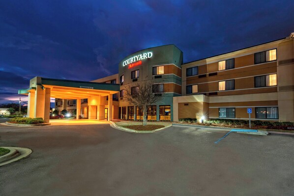 A Courtyard Marriott hotel with a well-lit entrance, a parking lot, and a small landscaped area with a tree. - Courtyard by Marriott Alexandria (Alexandria)