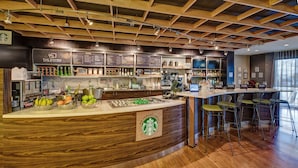 A Starbucks coffee shop interior with a wooden counter, bar stools, and a menu board. - Courtyard by Marriott Alexandria (Alexandria)