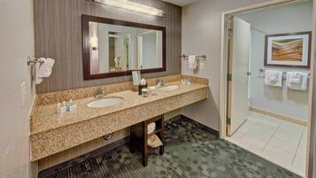 A hotel bathroom with two sinks, a large mirror, and a towel rack.
