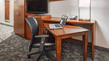 Une chambre d’hôtel équipée d’un bureau en bois, d’un ordinateur portable, d’une télévision et d’un téléphone.