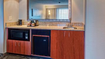 A compact kitchenette with a microwave, coffee maker, and a small refrigerator.