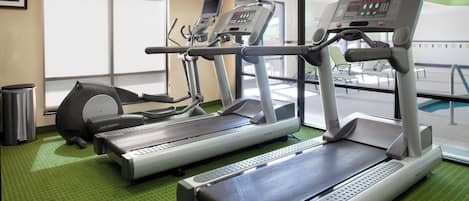 Un gimnasio con cintas de correr, una máquina de remo y una bicicleta estática.