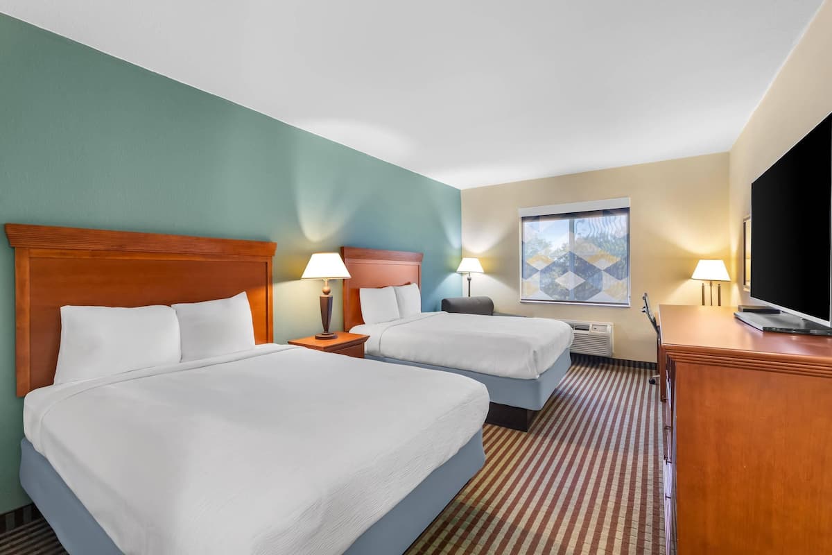 Habitación de hotel con dos camas, televisión y ventana con vista.