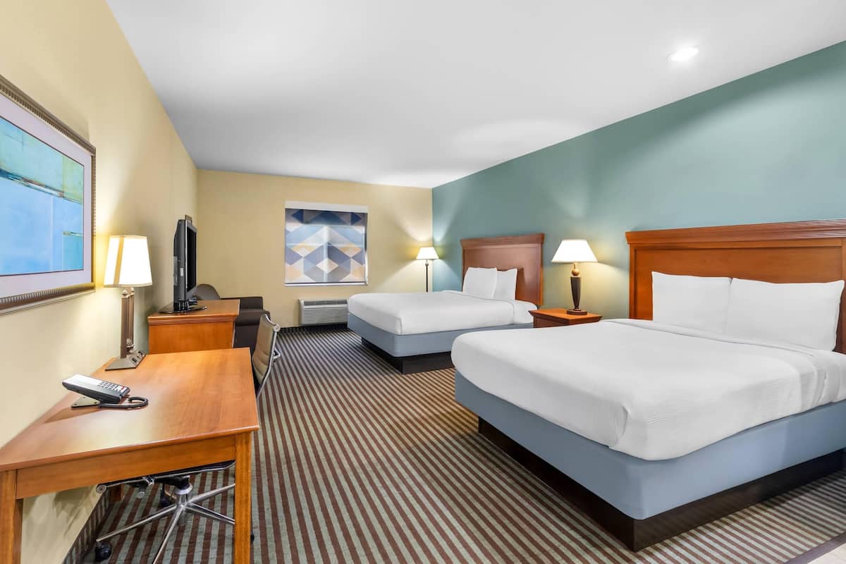 Habitación de hotel con dos camas, un escritorio con teléfono, televisión y dos lámparas.
