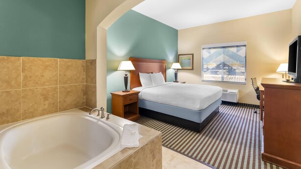 A hotel room with a large bathtub, two beds, a desk, and a television. - Quality Inn & Suites - Marlin (Marlin)