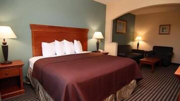 A hotel room with a large bed, two bedside tables with lamps, a chair, and a small table.