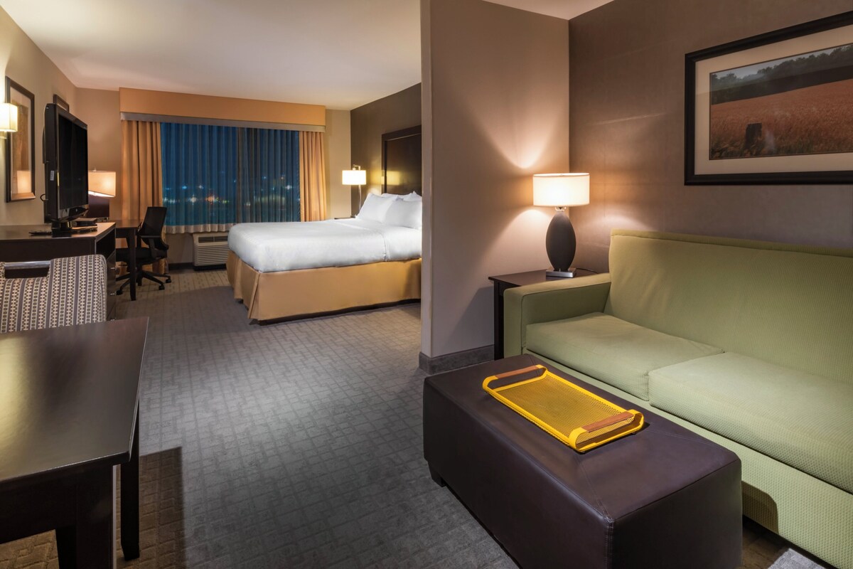 A hotel room with a bed, a desk with a computer, a sofa, and a TV.