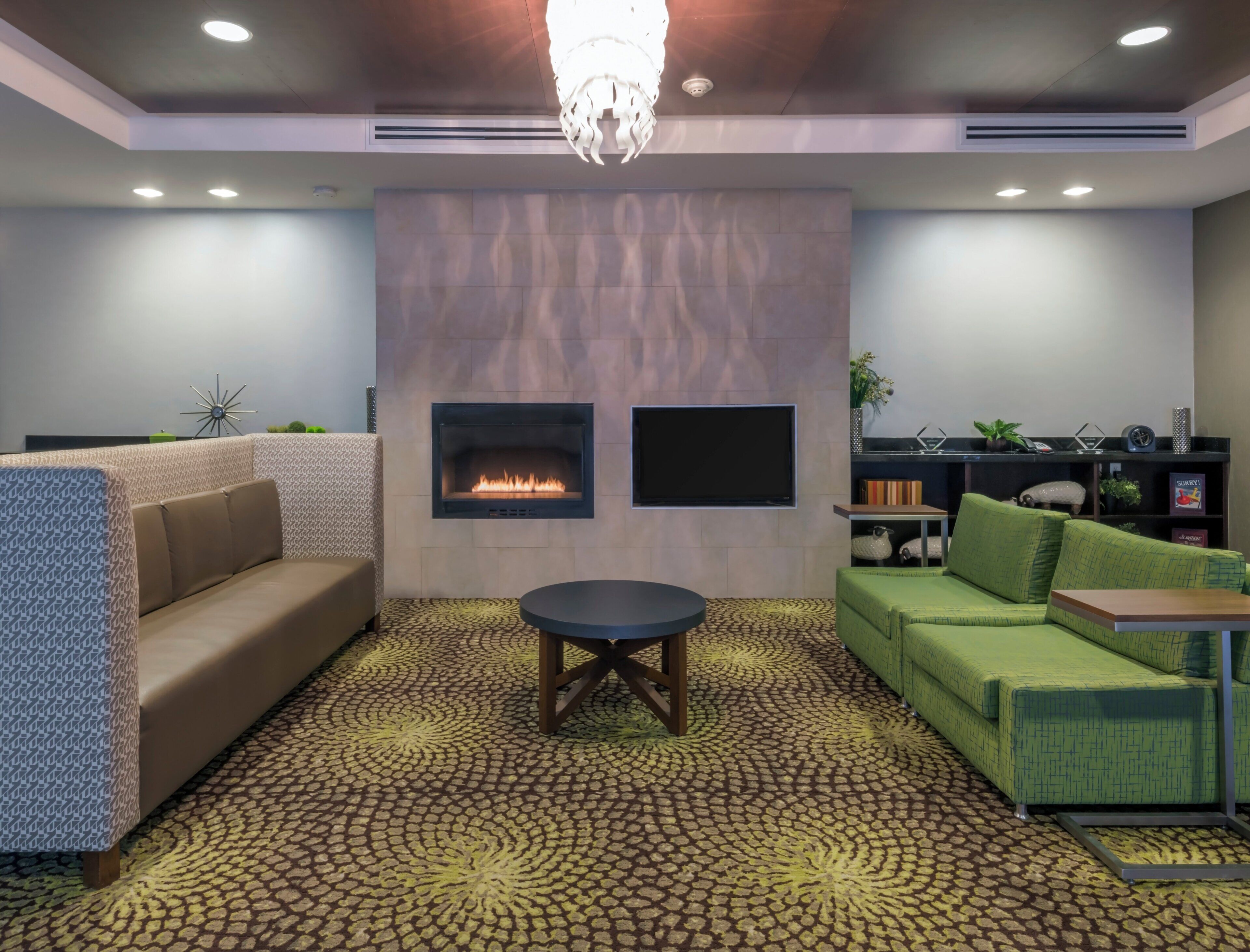 A modern lounge area with a fireplace, sofas, a coffee table, and a patterned floor.