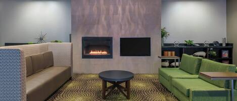 A modern lounge area with a fireplace, sofas, a coffee table, and a patterned floor.
