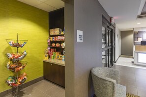 A hotel lobby with a snack area, a seating area, and a sign indicating the market is open 24 hours. - Holiday Inn Express Hotel & Suites Hays by IHG (Hays)
