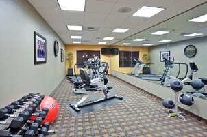 Un gimnasio con equipo de ejercicio, un espejo grande y suelo estampado.