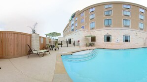 A hotel with a swimming pool, outdoor seating, and a stone facade. - Holiday Inn Express & Suites Houston South near Pearland by IHG (Houston)