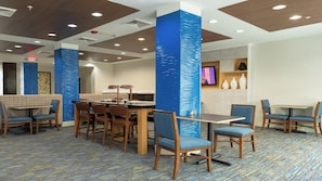 A hotel dining area with a long table, chairs, and a TV screen. - Holiday Inn Express & Suites Houston South near Pearland by IHG (Houston)