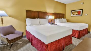 A hotel room with two beds, a chair, a lamp, and a painting on the wall.