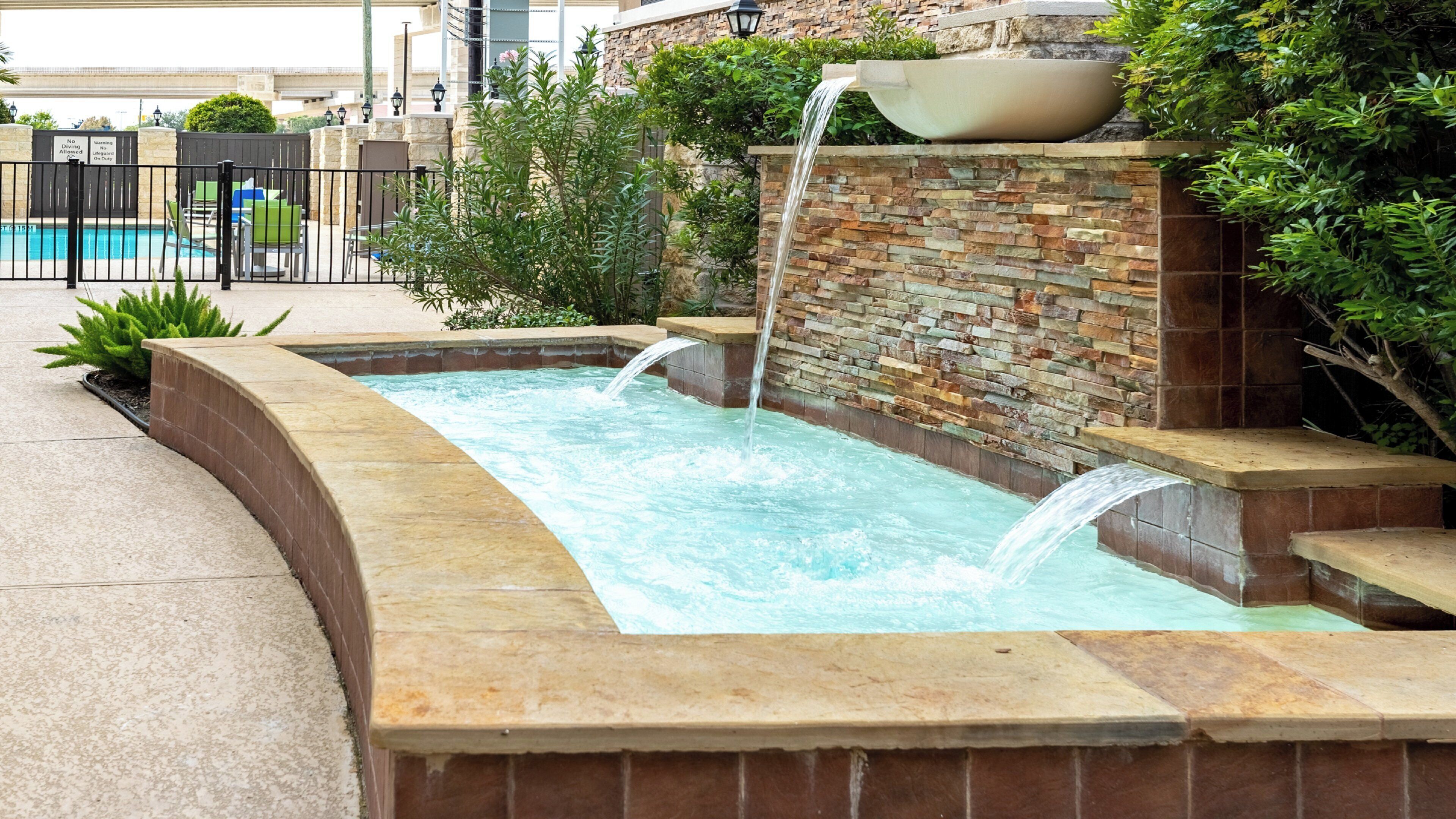 A spa area with a pool, a waterfall feature, and a stone wall.