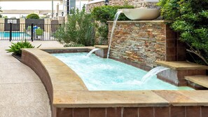 Un área de spa con piscina, cascada y pared de piedra.