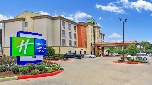 A Holiday Inn Express & Suites building with a large sign, parking lot, and a covered parking area. - Holiday Inn Express & Suites Houston South near Pearland by IHG (Houston)