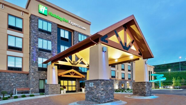 A Holiday Inn Express & Suites building with a stone facade, large windows, and a prominent entrance with a wooden canopy. - Holiday Inn Express Hotel & Suites Great Falls by IHG (Great Falls)