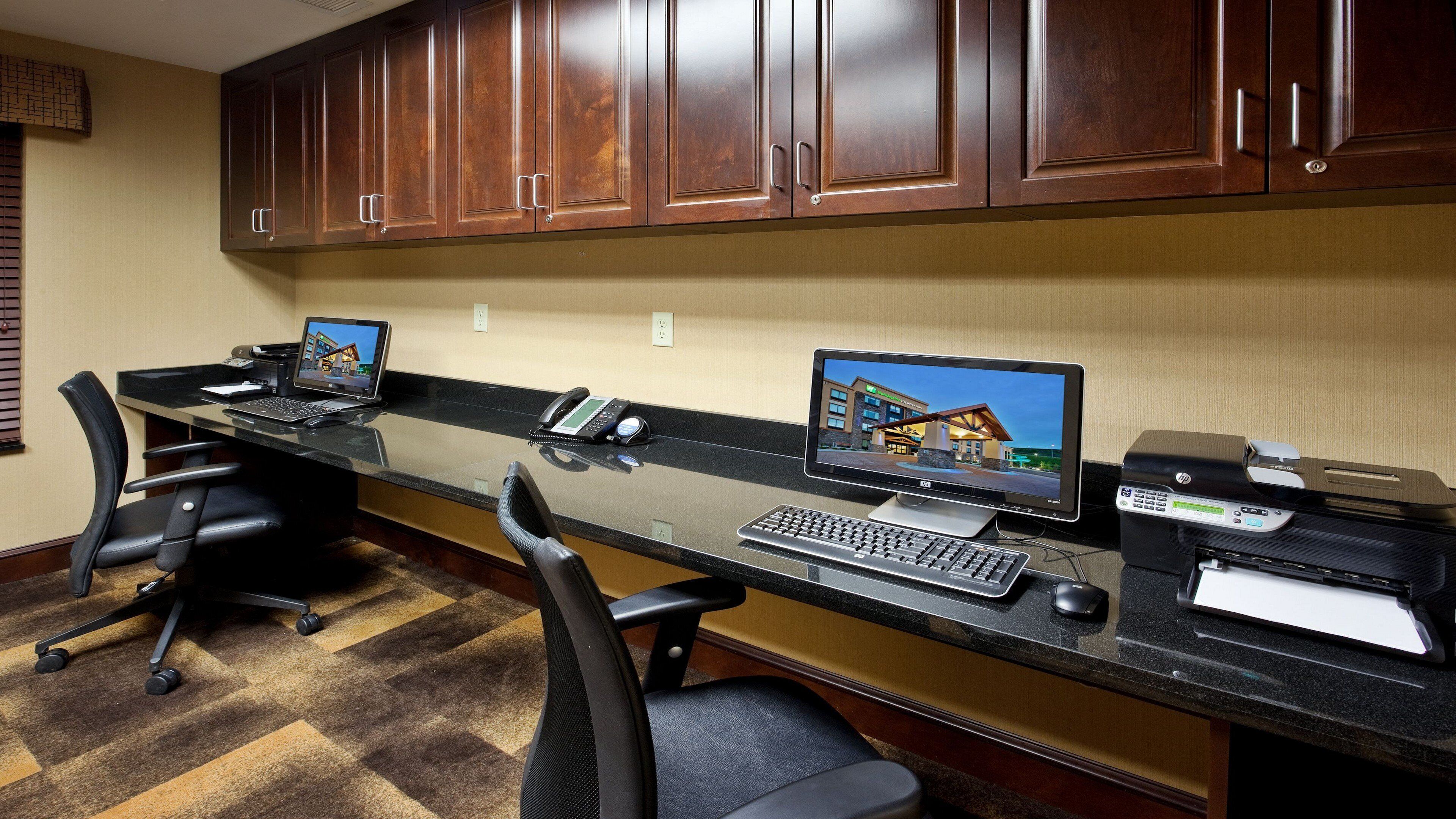 A hotel reception desk with two computer monitors, a printer, and a telephone.