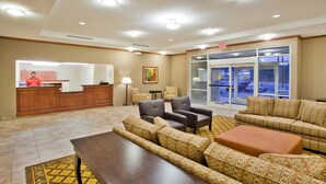 A hotel lobby with a reception desk, seating area, and a large window overlooking the parking area.
