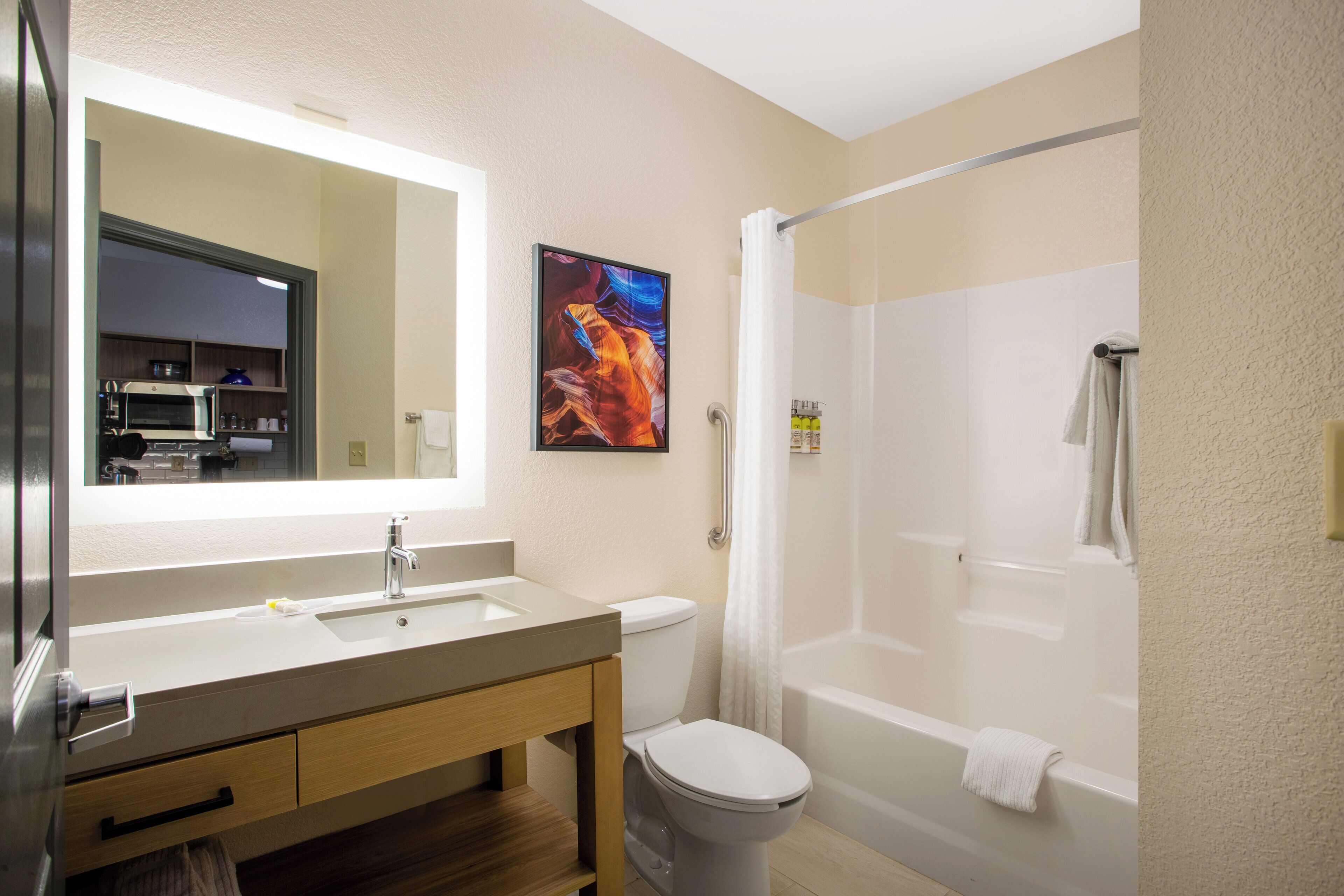A bathroom with a sink, mirror, toilet, and shower.