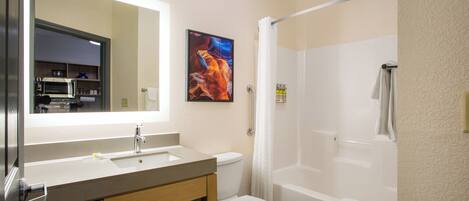 A bathroom with a sink, mirror, toilet, and shower.
