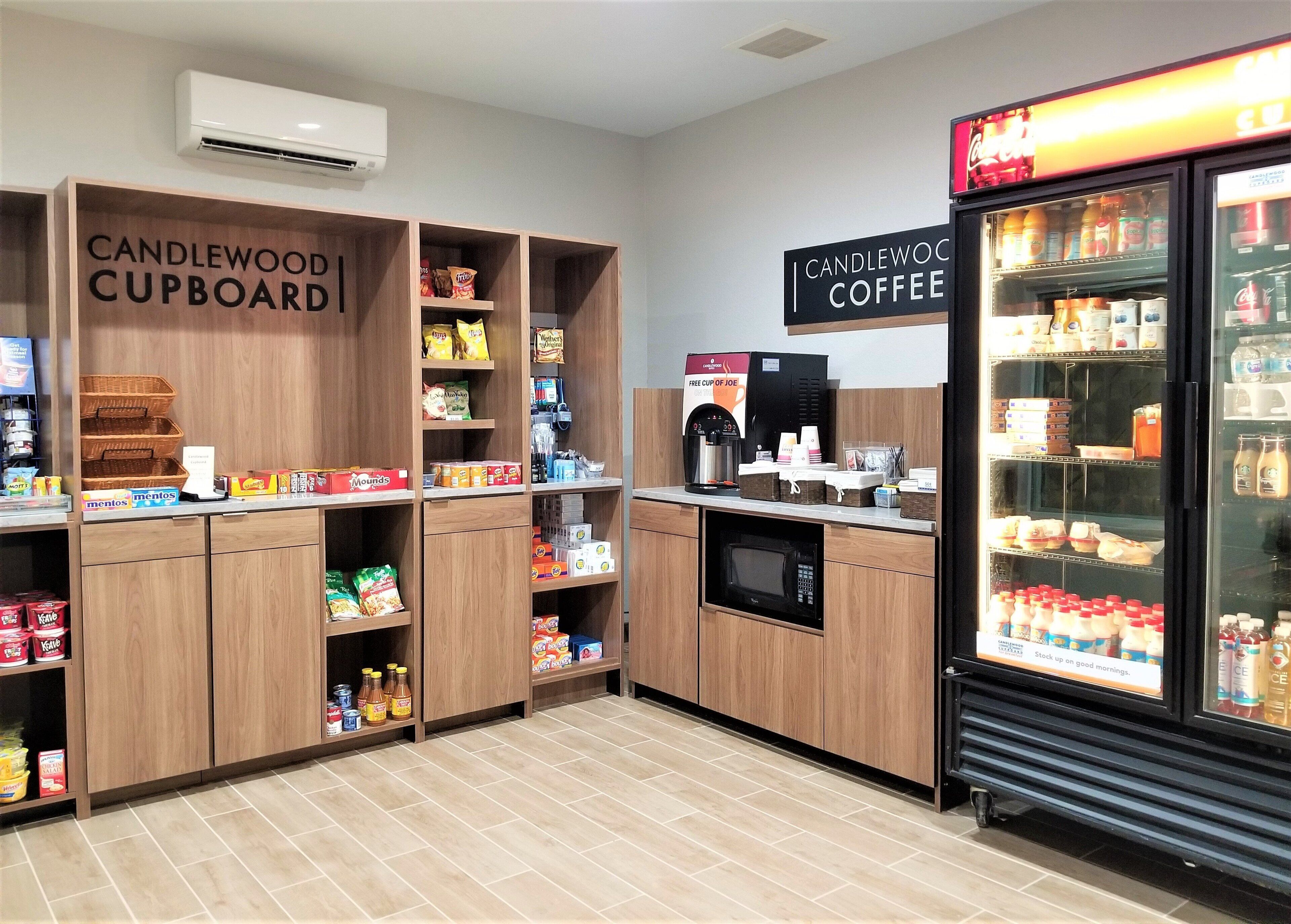 Una kitchenette con secciones identificadas para 'CANDLEWOOD CUPBOARD' y 'CANDLEWOOD COFFEE', provista de refrigerios, condimentos y bebidas.