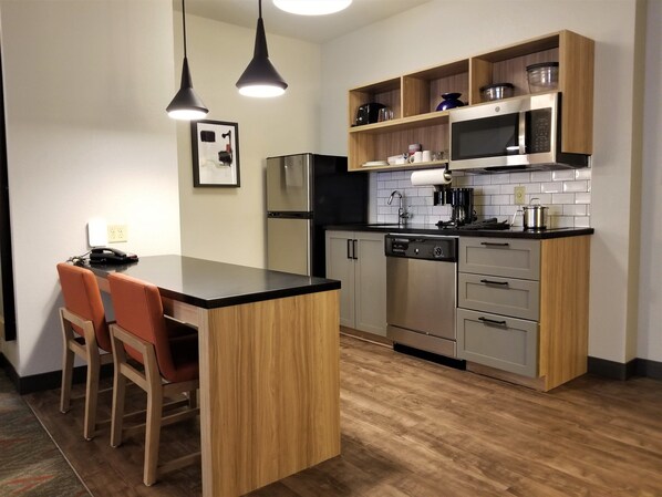 A modern kitchen with a wooden island, built-in appliances, and pendant lighting. - Candlewood Suites Apex Raleigh Area by IHG (Apex)