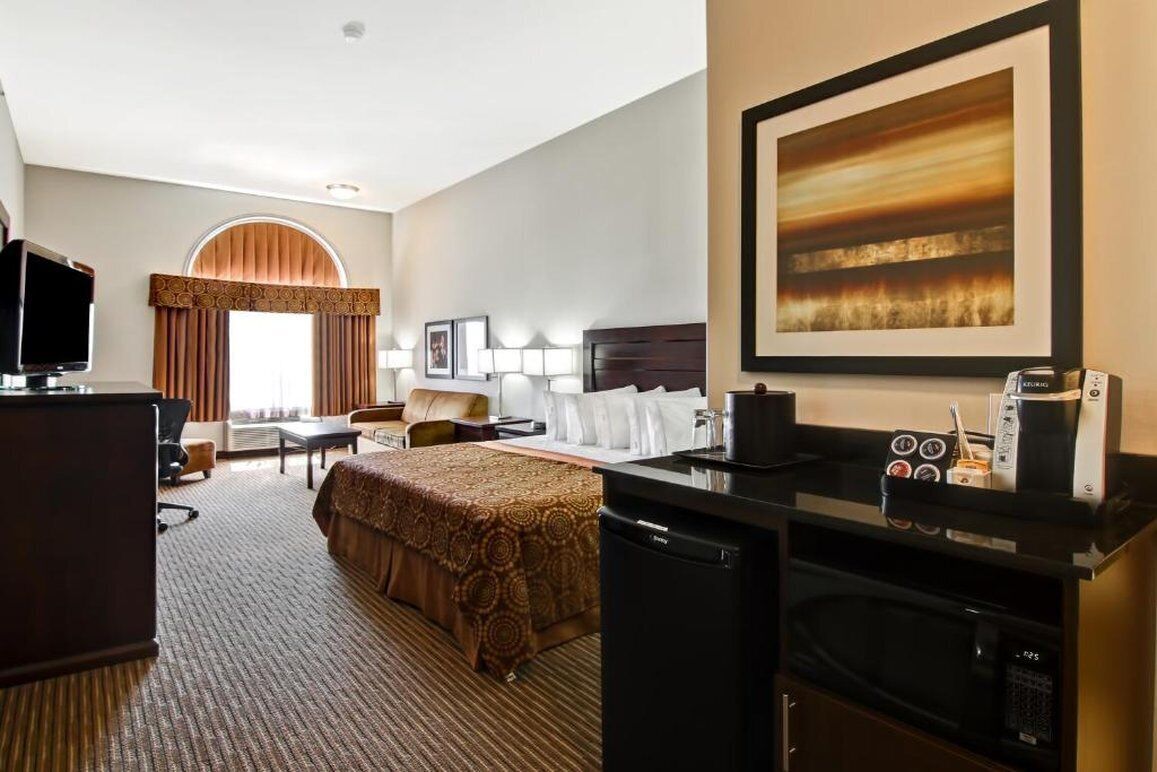 A hotel room with a bed, desk, microwave, and a large painting on the wall.