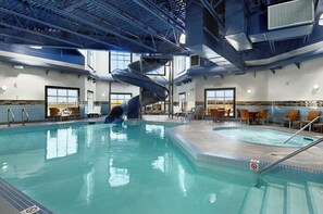 An indoor swimming pool with a slide, seating areas, and a view of the outdoors. - Moosomin Canalta (Moosomin)