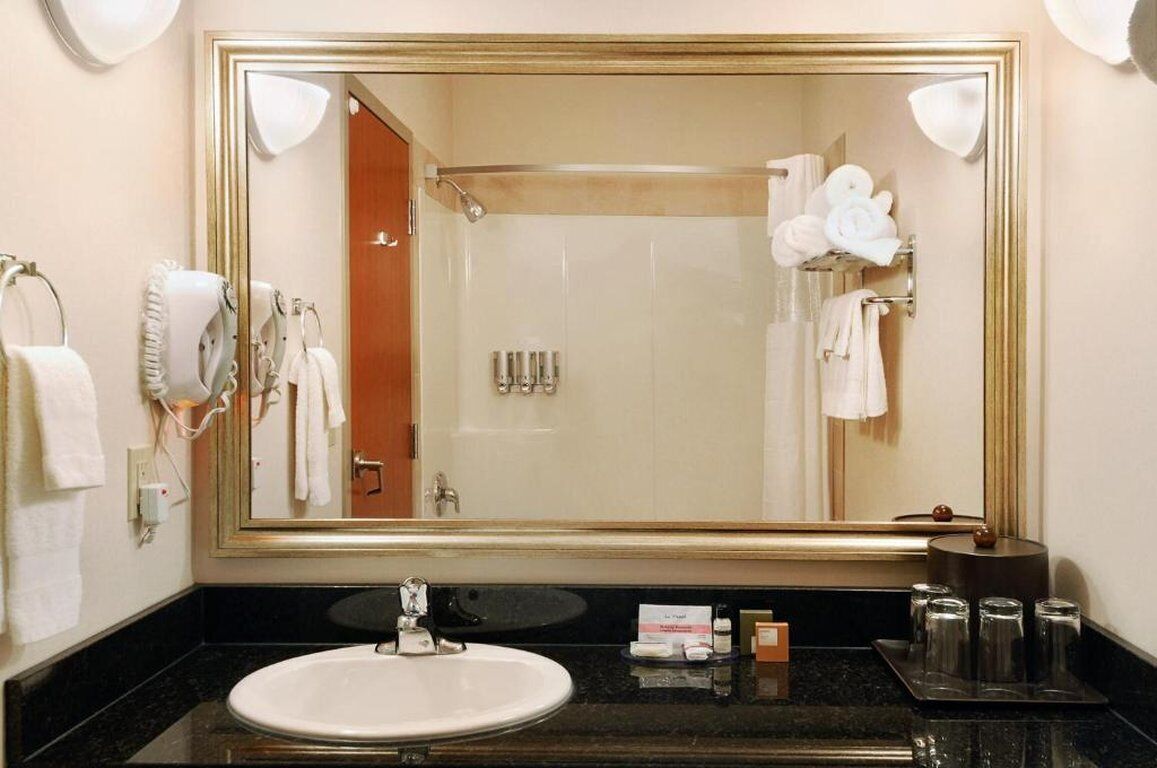 A bathroom with a large mirror, a sink, and a shower area.