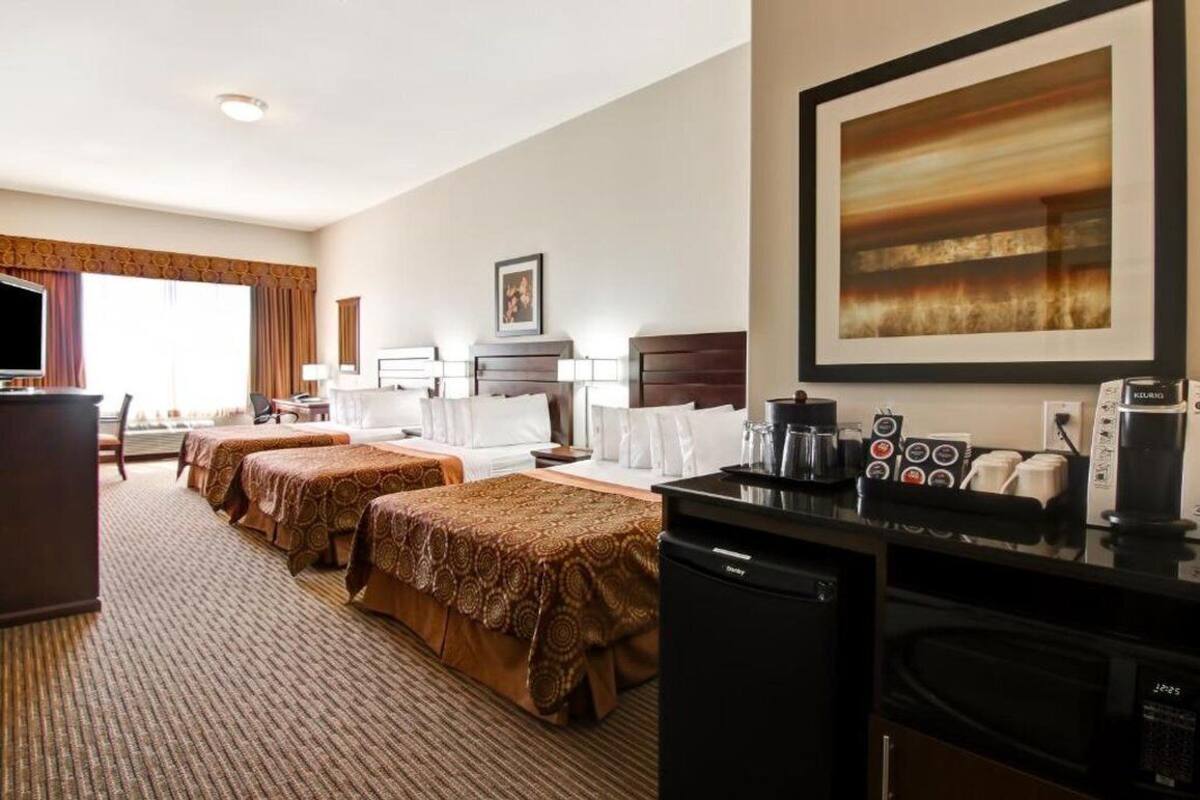 A hotel room with two beds, a desk, a coffee maker, and a TV.