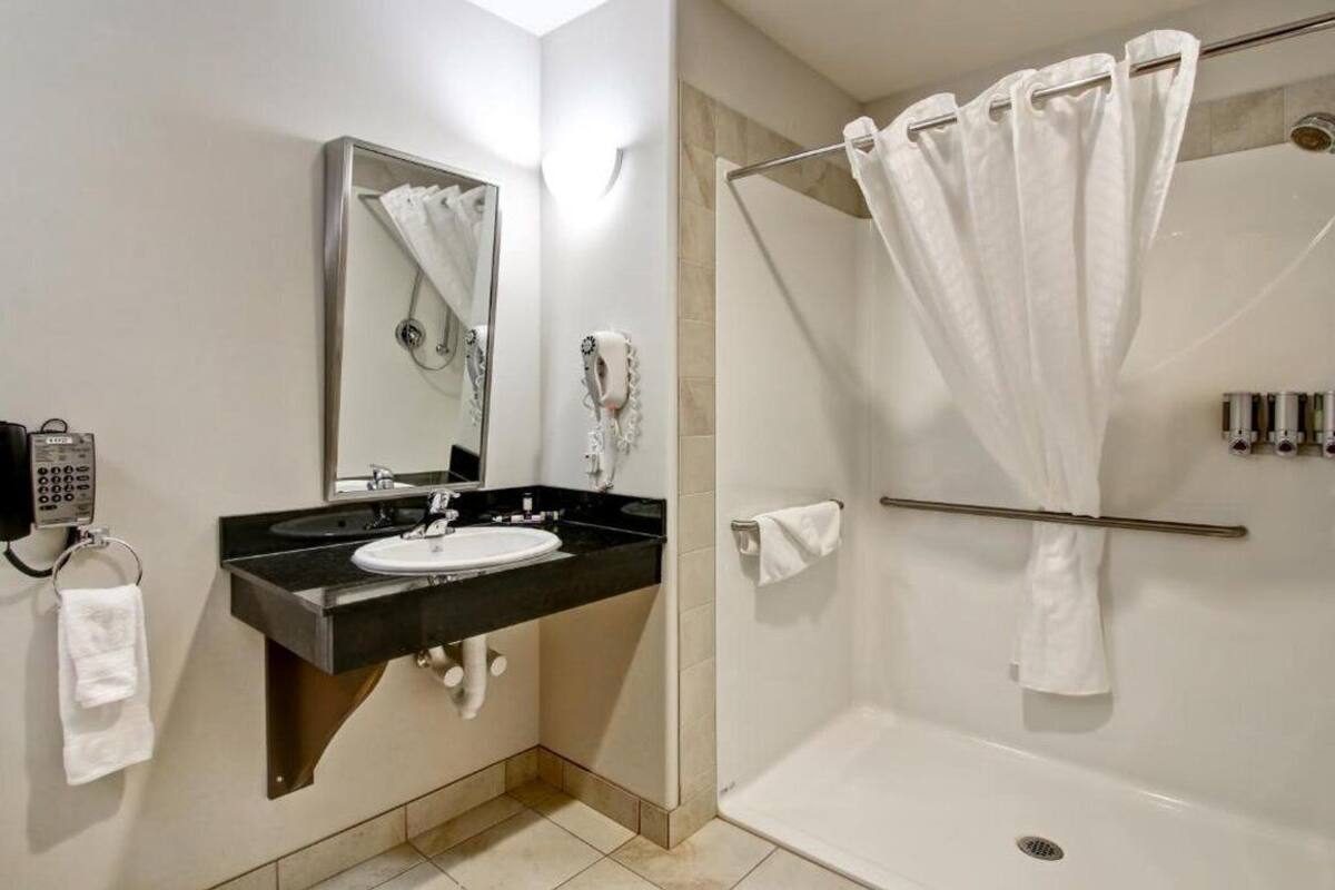 A modern bathroom with a sink, mirror, and shower.