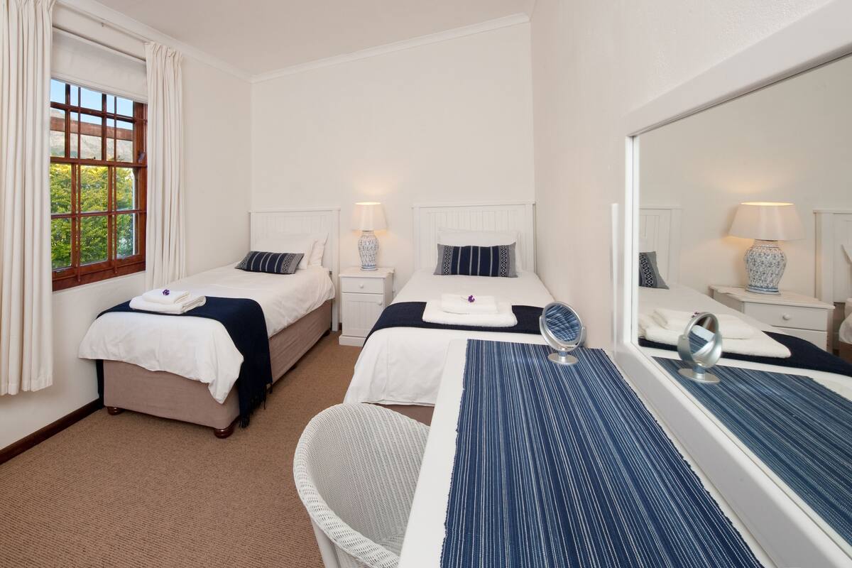 A hotel room with two beds, a large mirror, a desk, and a chair.
