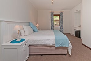 Quarto bem arrumado com uma cama, mesas de cabeceira, cômoda e janela com cortinas.