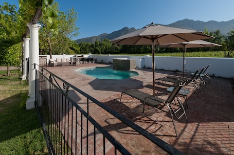 Alberca al aire libre, sombrillas en la alberca y camastros