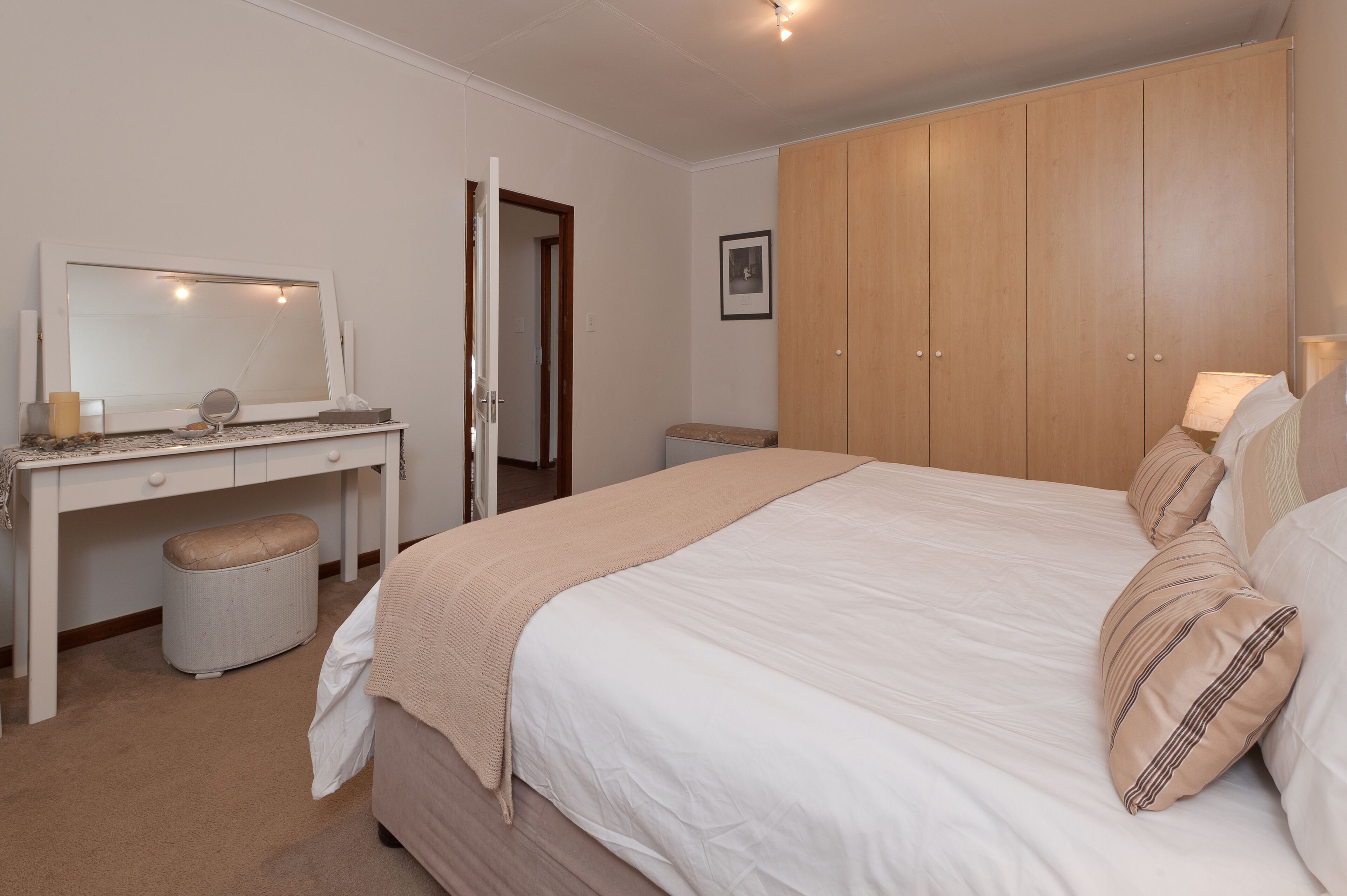 Une chambre à coucher comprenant un lit, un bureau avec un miroir, une armoire et une table de chevet.
