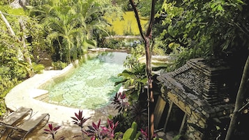 Una piscina rodeada de exuberante vegetación y arquitectura de piedra.