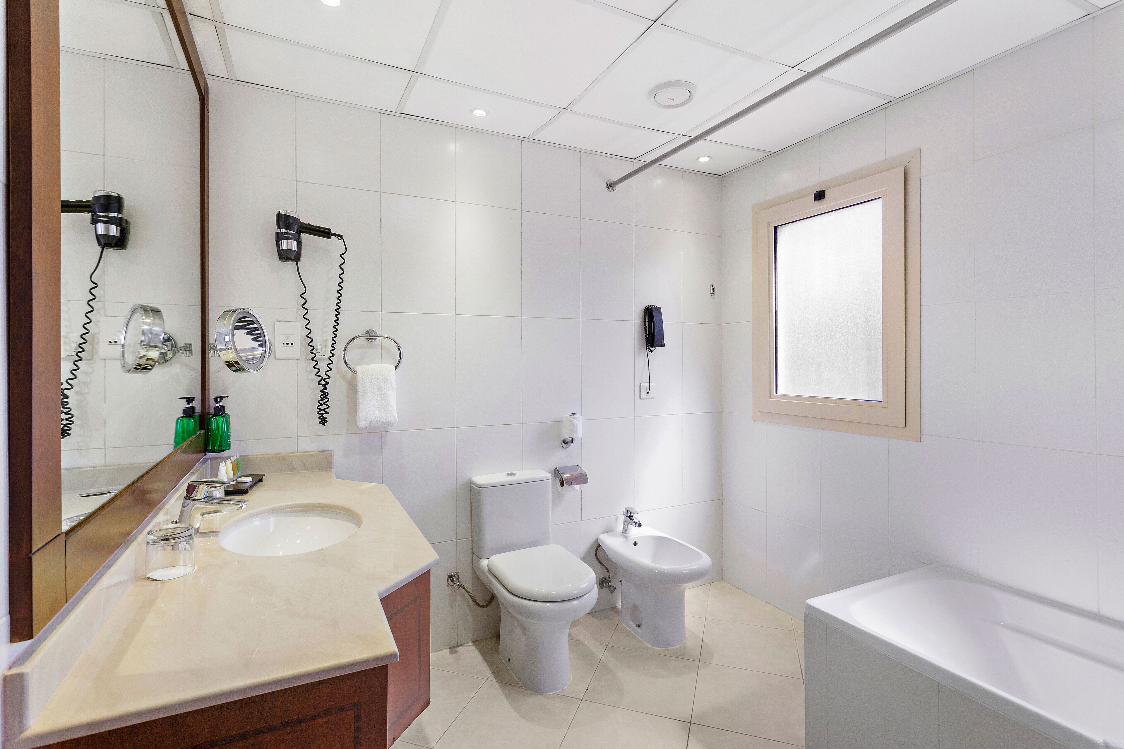 Une salle de bain moderne équipée d’un lavabo, de toilettes, d’un bidet et d’une baignoire.