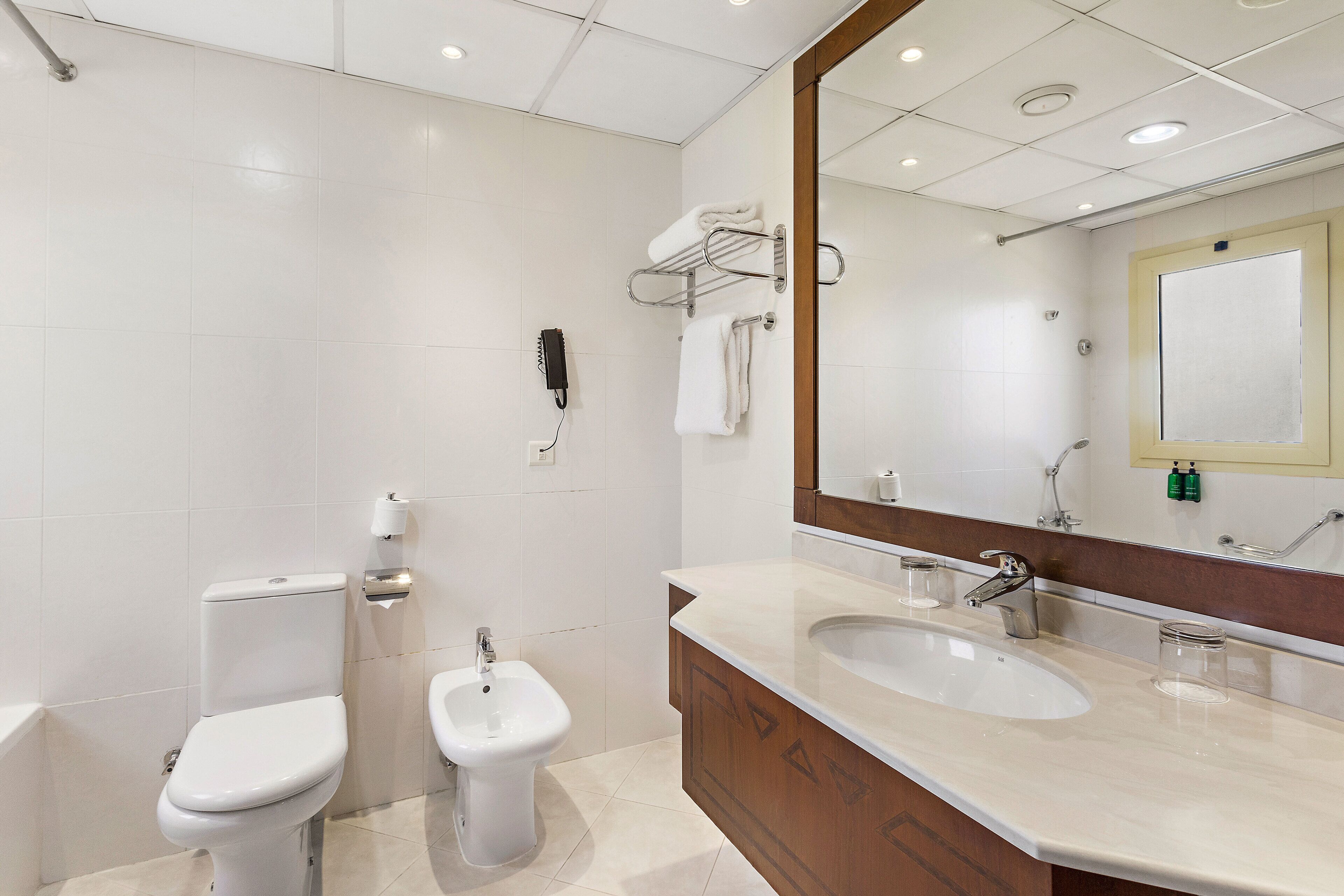 Un bany modern amb vàter, bidet i un lavabo amb mirall a la part superior.