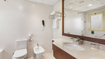 Un bany modern amb vàter, bidet i un lavabo amb mirall a la part superior.
