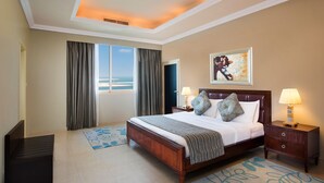 A hotel room with a large bed, two bedside tables, a nightstand, a bench, and a view of the ocean through the window. - Al Hamra Village Hotel (Ras Al Khaimah)