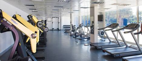 Un gimnasio con cintas de correr, máquinas de pesas y mancuernas.