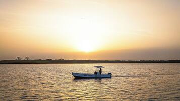 Una embarcación con la leyenda "KEUR SALOM" y "SUI MANGA" en su costado, navegando sobre aguas tranquilas durante el atardecer.