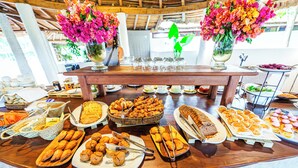Una mesa de buffet con diversos alimentos y dos grandes arreglos florales.