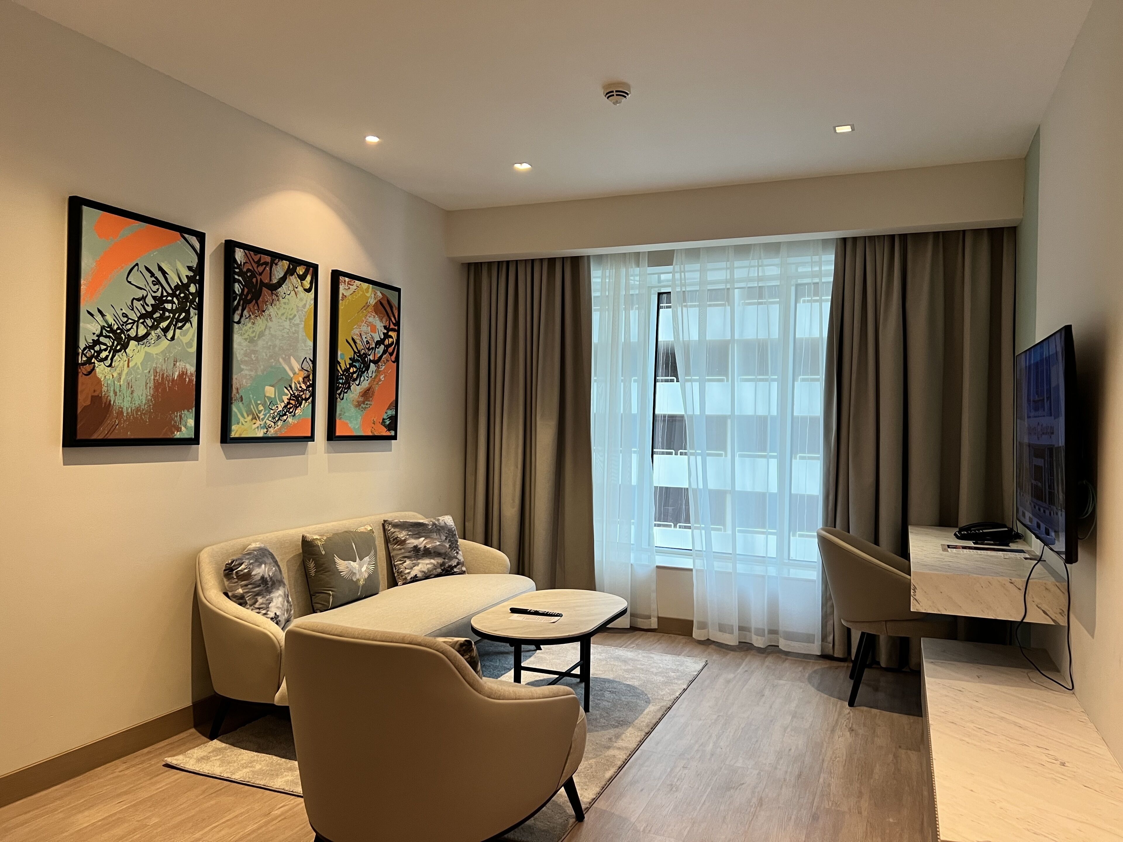 A modern living room with a sofa, a small table, a TV, and artwork on the wall.