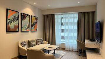 A modern living room with a sofa, a small table, a TV, and artwork on the wall.